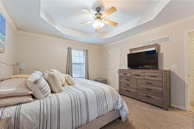 bedroom with ornamental molding, light carpet, ceiling fan, and a tray ceiling