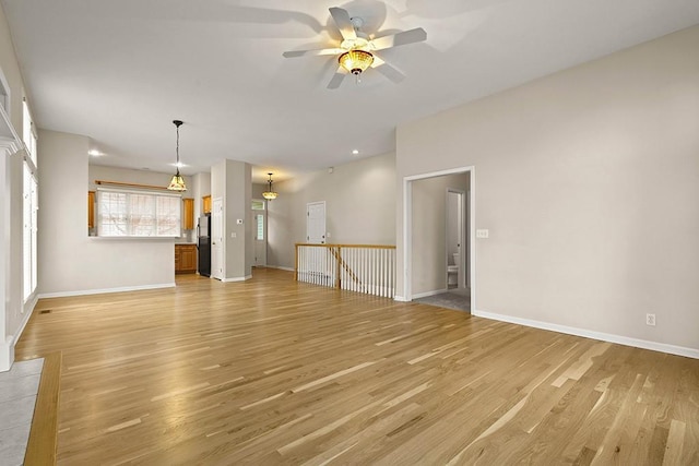 unfurnished living room with light wood-style flooring, baseboards, and a ceiling fan