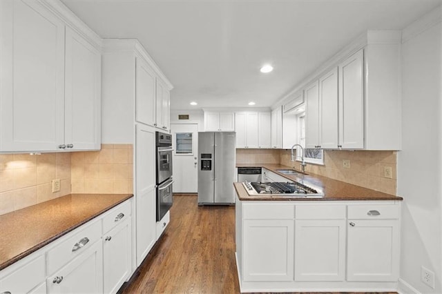 kitchen featuring sink, dark hardwood / wood-style floors, stainless steel appliances, decorative backsplash, and white cabinets