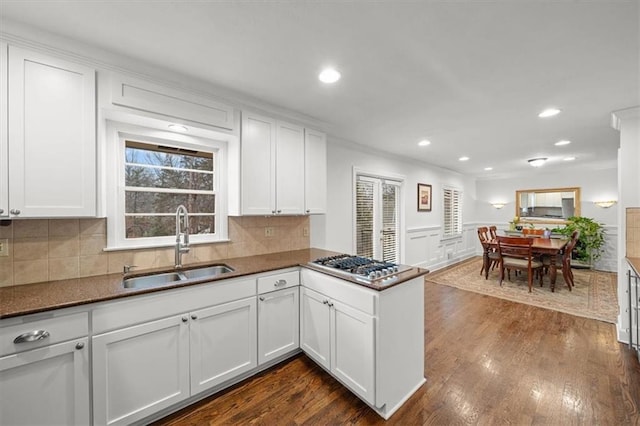 kitchen with dark hardwood / wood-style floors, white cabinetry, sink, stainless steel gas cooktop, and kitchen peninsula