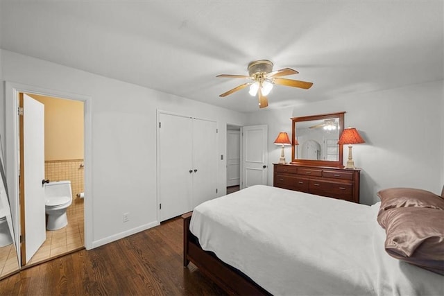 bedroom featuring tile walls, dark hardwood / wood-style floors, ceiling fan, and ensuite bathroom