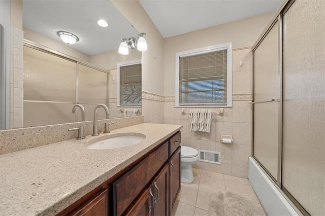 full bathroom featuring toilet, combined bath / shower with glass door, tile walls, vanity, and tile patterned flooring