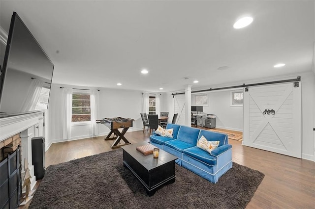 living room with hardwood / wood-style floors, a stone fireplace, and a barn door