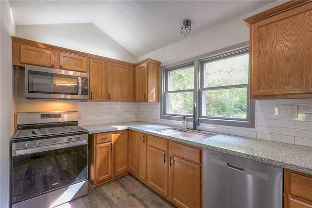 kitchen with lofted ceiling, sink, dark hardwood / wood-style flooring, stainless steel appliances, and decorative backsplash