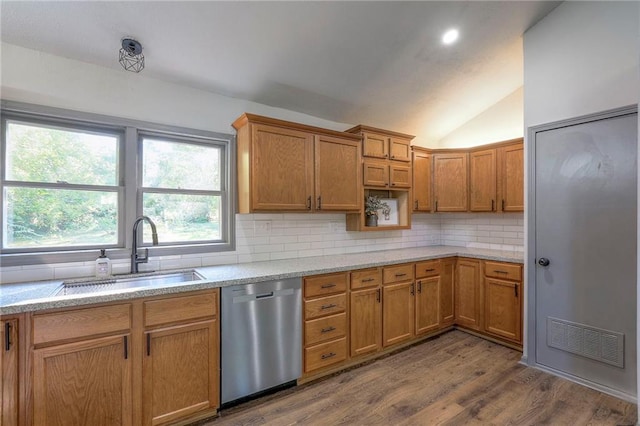 kitchen with sink, dishwasher, wood-type flooring, decorative backsplash, and vaulted ceiling