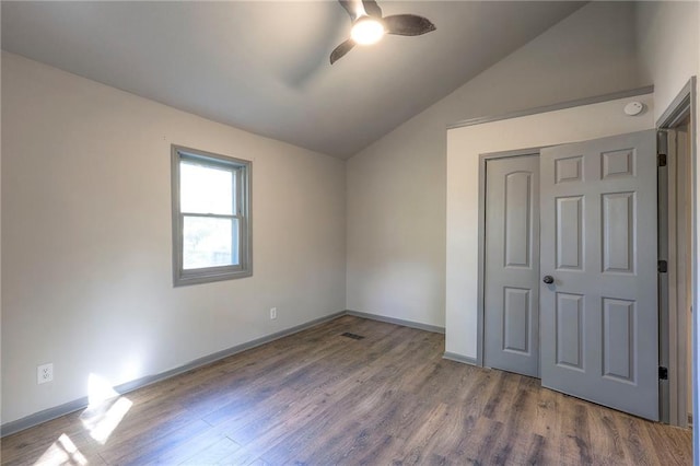 unfurnished bedroom with lofted ceiling, hardwood / wood-style floors, ceiling fan, and a closet