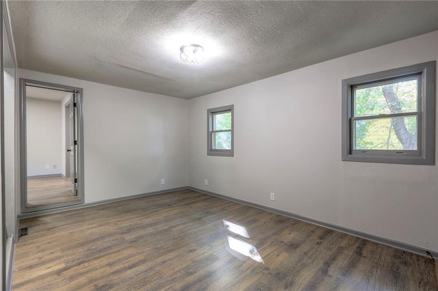 spare room with dark hardwood / wood-style floors and a textured ceiling