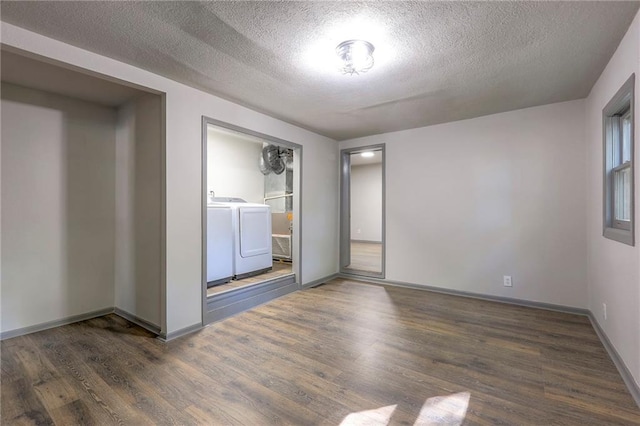 empty room featuring dark hardwood / wood-style floors, washing machine and clothes dryer, and a textured ceiling