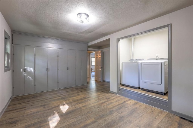 unfurnished bedroom with dark hardwood / wood-style flooring, a closet, washer and dryer, and a textured ceiling