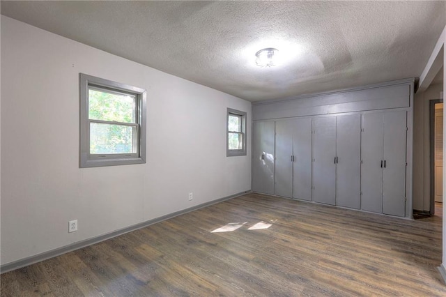 unfurnished bedroom featuring dark wood-type flooring, a textured ceiling, and a closet