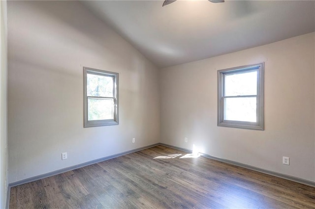 spare room featuring plenty of natural light, dark wood-type flooring, lofted ceiling, and ceiling fan