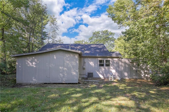 rear view of house featuring a yard and central AC