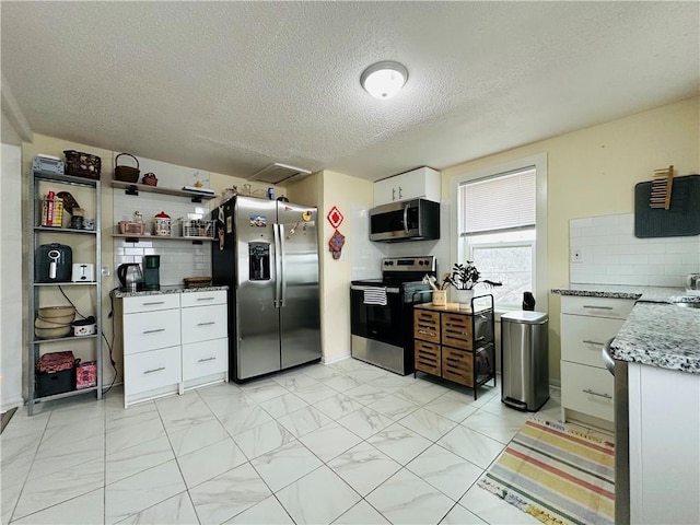 kitchen featuring white cabinetry, tasteful backsplash, light stone counters, a textured ceiling, and stainless steel appliances