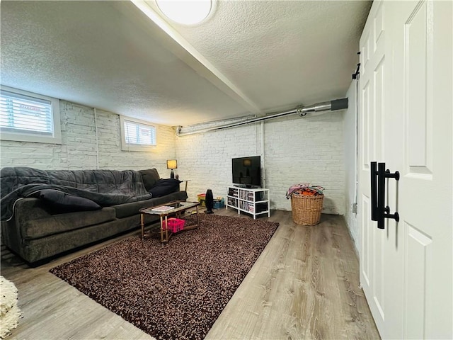 living room featuring brick wall, a textured ceiling, and light wood-type flooring