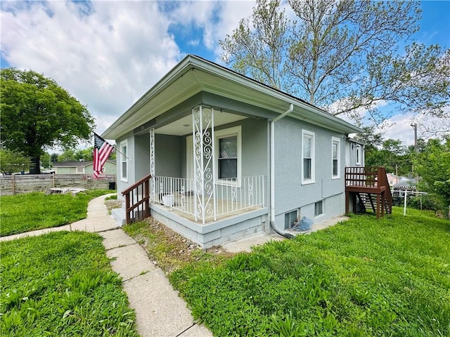 view of front of property featuring covered porch, fence, a front yard, and stucco siding