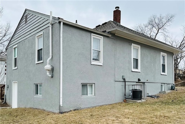 view of property exterior featuring a yard, a chimney, and stucco siding