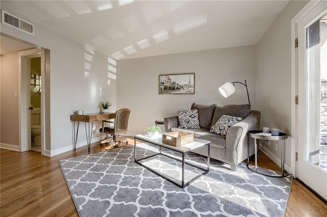 living room featuring wood finished floors, visible vents, a wealth of natural light, and baseboards