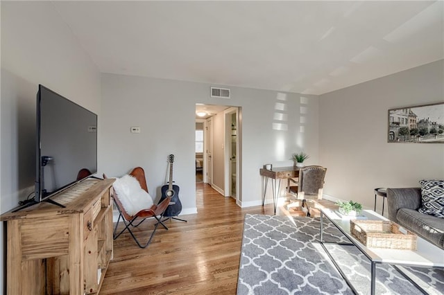 living area with light wood-style flooring, baseboards, and visible vents