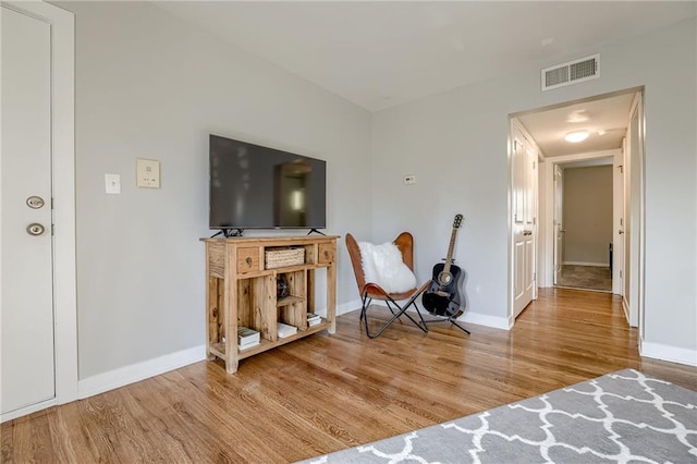 living area featuring visible vents, baseboards, and wood finished floors