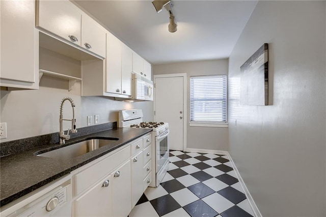 kitchen with light floors, rail lighting, white appliances, white cabinetry, and a sink