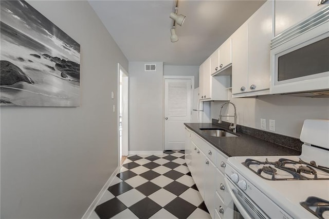 kitchen with tile patterned floors, visible vents, a sink, dark countertops, and white appliances