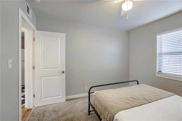 bedroom with visible vents, baseboards, light colored carpet, and a ceiling fan