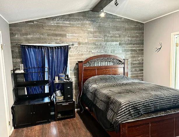 bedroom featuring hardwood / wood-style flooring, crown molding, and vaulted ceiling with beams