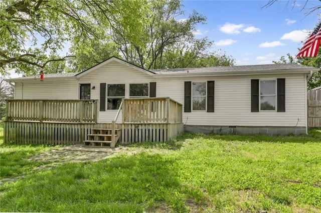 rear view of house featuring a deck, a lawn, and a shingled roof