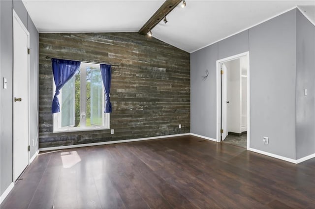 unfurnished living room featuring wood walls, wood finished floors, an accent wall, baseboards, and track lighting