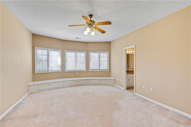 empty room featuring baseboards, a textured ceiling, a healthy amount of sunlight, and a ceiling fan