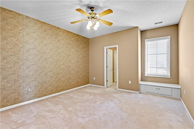 spare room with visible vents, a ceiling fan, a textured ceiling, baseboards, and light colored carpet