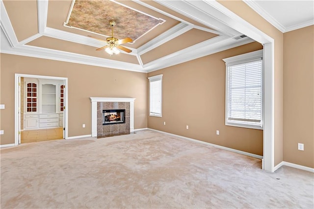 unfurnished living room with baseboards, carpet, ornamental molding, a tile fireplace, and a raised ceiling