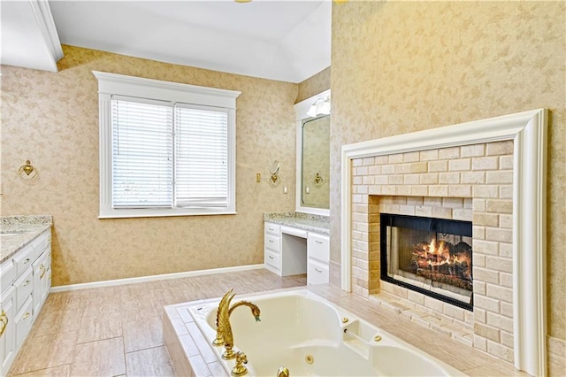 full bathroom with a tub with jets, wallpapered walls, vanity, and baseboards