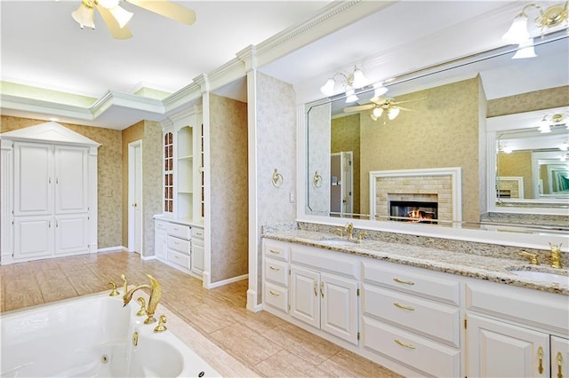 bathroom featuring wallpapered walls, a glass covered fireplace, a ceiling fan, and a sink