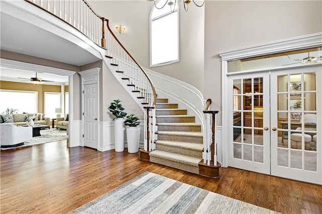 interior space with a high ceiling, a decorative wall, wood finished floors, and french doors