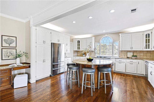 kitchen with light stone counters, glass insert cabinets, appliances with stainless steel finishes, and crown molding