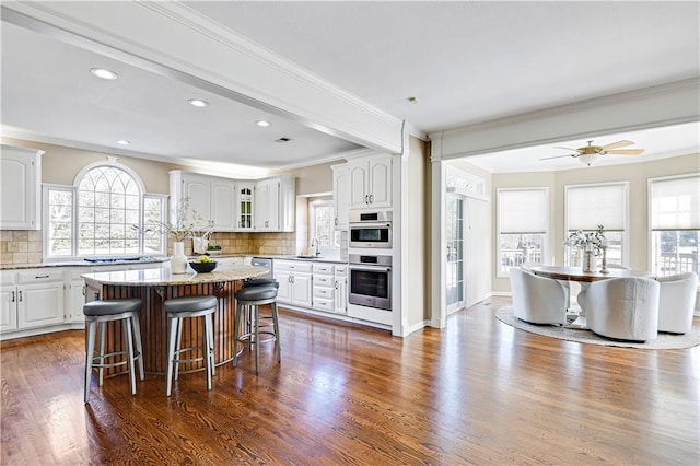 kitchen with crown molding, a kitchen breakfast bar, dark wood-style flooring, and a kitchen island