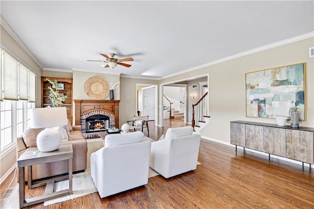 living room featuring stairway, ornamental molding, a fireplace, and wood finished floors