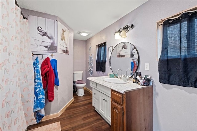 bathroom with vanity, wood finished floors, toilet, and baseboards