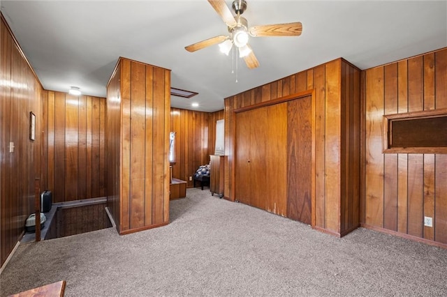 spare room with light carpet, wood walls, and ceiling fan