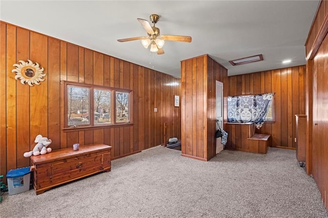 home theater featuring light carpet, ceiling fan, and wooden walls