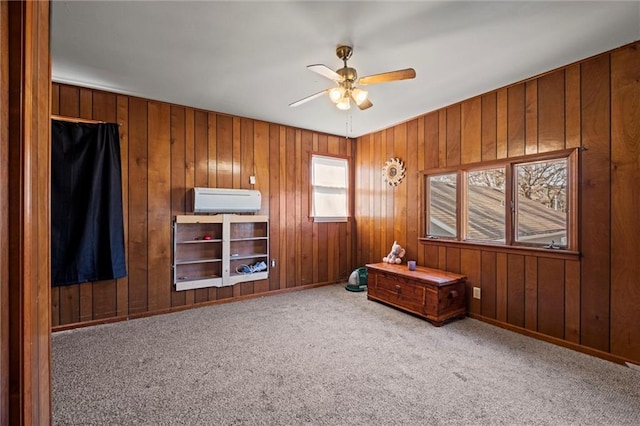 interior space with a wall unit AC, carpet, wooden walls, and a ceiling fan