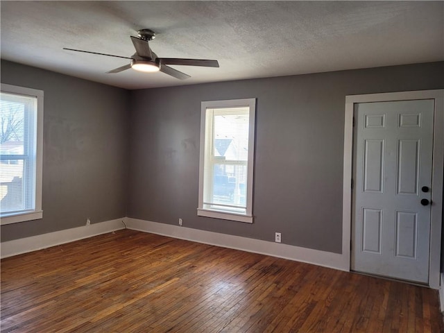 spare room with a ceiling fan, a textured ceiling, baseboards, and hardwood / wood-style flooring