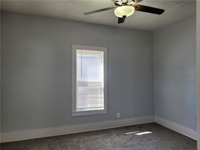 carpeted empty room featuring a ceiling fan and baseboards