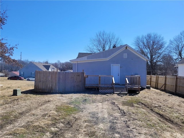 rear view of house featuring fence and a deck