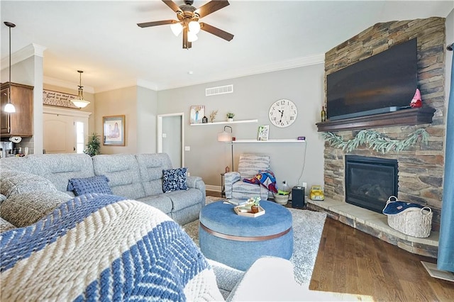 living room featuring ceiling fan, ornamental molding, a fireplace, and hardwood / wood-style floors