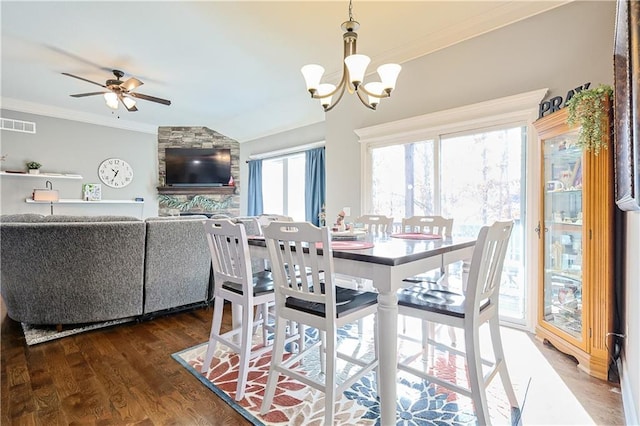 dining space featuring lofted ceiling, ornamental molding, dark hardwood / wood-style floors, and ceiling fan with notable chandelier