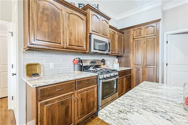 kitchen with crown molding, stainless steel appliances, tasteful backsplash, light stone countertops, and light tile patterned flooring