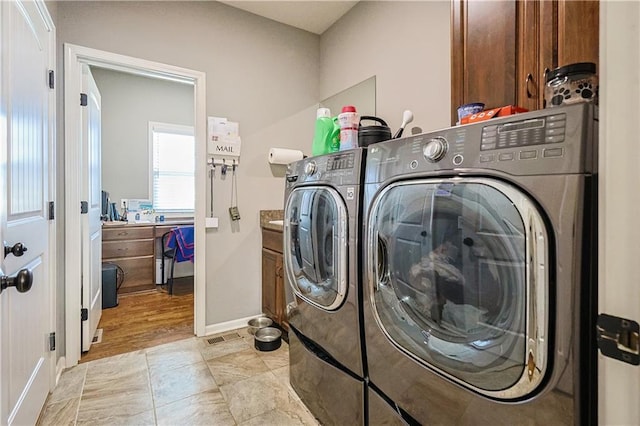 clothes washing area with washer and dryer and cabinets