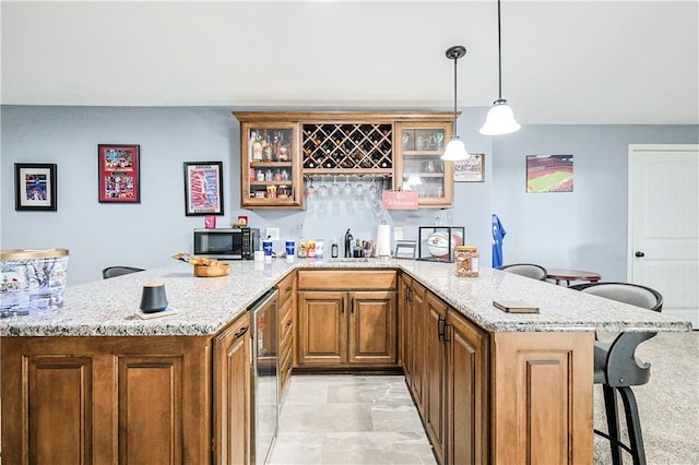 bar with decorative light fixtures, light stone countertops, and sink